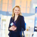 再入国許可を受けて、国際空港の中でパスポートを持って立っているビジネスウーマンの写真