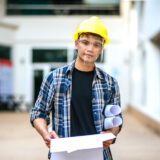 建設現場で図面を持って立っている特定技能ビザ（在留資格）の男性の写真